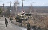 Ukrainian servicemen stand near an armored personnel carrier BTR-3 on the northwest of Kyiv, on February 24, 2022. (Daniel Leal/AFP)