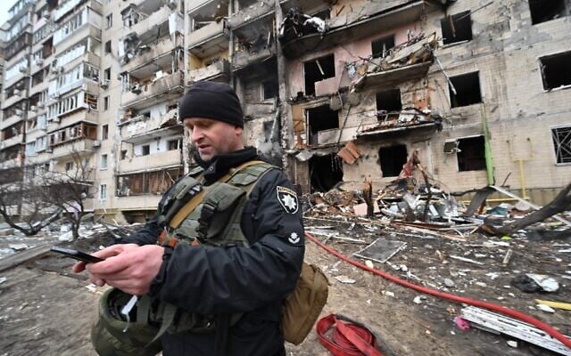 A police officer stands guard at a damaged residential building at Koshytsa Street, on the outskirts of the Ukrainian capital Kyiv, where a military shell allegedly hit, on February 25, 2022. (Genya Savilov/AFP) A police officer stands guard at a damaged residential building at Koshytsa Street, on the outskirts of the Ukrainian capital Kyiv, where a military shell allegedly hit, on February 25, 2022. (Genya Savilov/AFP)