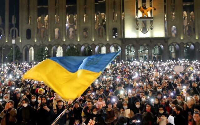 Demonstrators hold their smartphones with torches lit as a Ukranian flag is waved during a rally in support of Ukraine, in Tbilisi on February 25, 2022. (Vano Shlamov / AFP) Demonstrators hold their smartphones with torches lit as a Ukranian flag is waved during a rally in support of Ukraine, in Tbilisi on February 25, 2022. (Vano Shlamov / AFP)