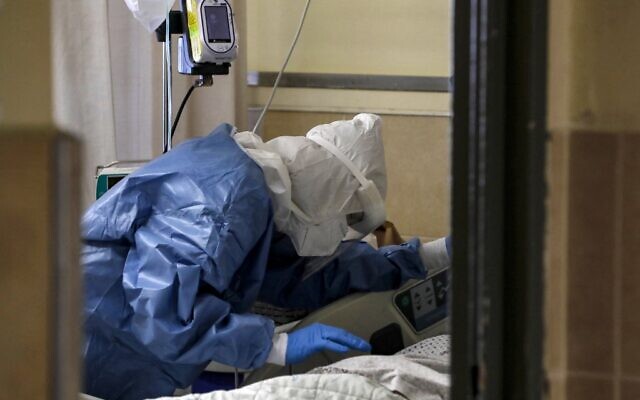 A medical worker tends to a patient infected by the coronavirus, in an isolation ward at the Ziv Medical Centre in Safed, on February 6, 2022 (JALAA MAREY / AFP) A medical worker tends to a patient infected by the coronavirus, in an isolation ward at the Ziv Medical Centre in Safed, on February 6, 2022 (JALAA MAREY / AFP)