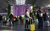 Travelers wait at the the departures board ahead of their flights at the Boryspil airport some 30 kilometers (some 18 miles) outside Kyiv on February 13, 2022. (Sergei Supinsky / AFP)