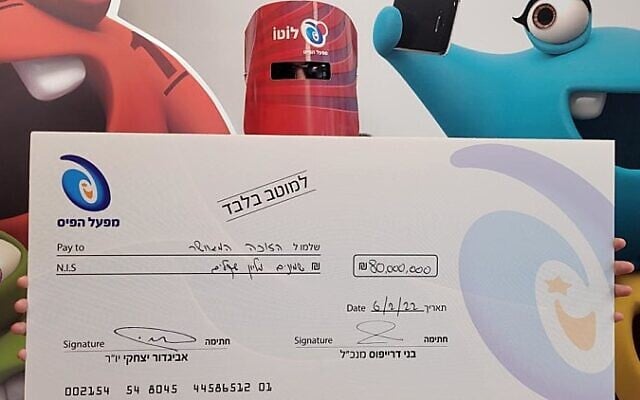 A man who won NIS 80 million in Israel's largest lottery jackpot poses with a giant check at the offices of the Mifal HaPais national lottery on February 6, 2022 (Mifal HaPais) A man who won NIS 80 million in Israel's largest lottery jackpot poses with a giant check at the offices of the Mifal HaPais national lottery on February 6, 2022 (Mifal HaPais)