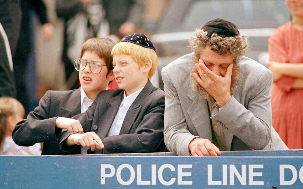 Orthodox Jews react as a crowd of angry black demonstrators approach the Lubavitcher Synagogue in the Crown Heights section on Brooklyn, August 25, 1991. (AP Photo/Mark Lennihan)