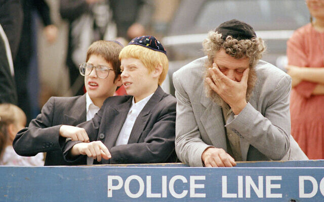 Orthodox Jews react as a crowd of angry black demonstrators approach the Lubavitcher Synagogue in the Crown Heights section on Brooklyn, August 25, 1991. (AP Photo/Mark Lennihan)