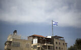 Illustrative: In this March 13, 2019, photo, an Israeli flag flies on a building in East Jerusalem's Mount of Olives. (AP Photo/Ariel Schalit)