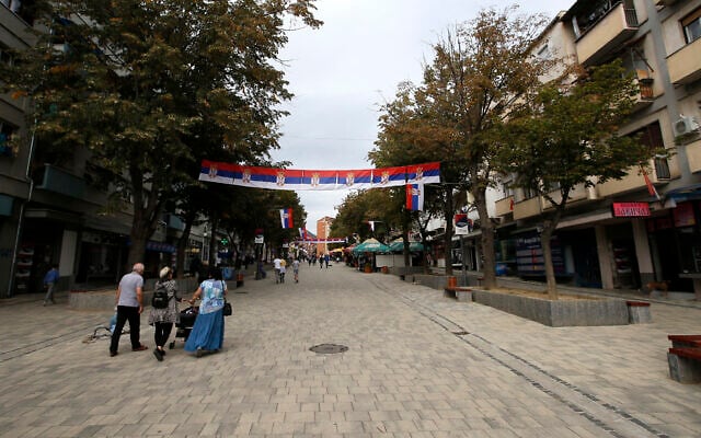 People walk through a street in Mitrovica, Kosovo, Oct. 5, 2019. (AP Photo/Darko Vojinovic)