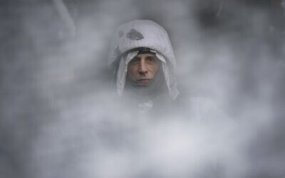 A Ukrainian serviceman, seen through a camouflage mesh, stands at a frontline position in the Luhansk region, eastern Ukraine, Saturday, Jan. 29, 2022. (AP Photo/Vadim Ghirda)