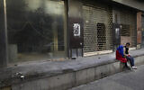 Beggars sit in front of shops that closed for good after the economic crisis, on Hamra Street, in Beirut, Lebanon, January 12, 2022. (AP Photo/Hussein Malla)