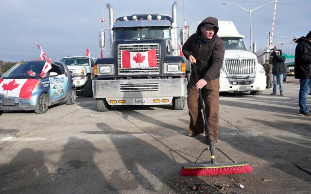 A protester sweeps up in preparation of police enforcing an injunction against their demonstration, which has blocked traffic across the Ambassador Bridge by protesters against COVID-19 restrictions, in Windsor, Ont., Feb. 12, 2022. (The Canadian Press via AP)