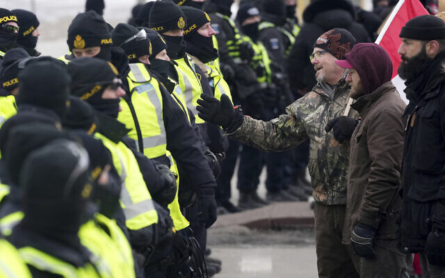 A protester attempts to speak with police officers as they enforce an injunction against their demonstration, which has blocked traffic across the Ambassador Bridge by protesters against COVID-19 restrictions, in Windsor, Ont., Feb. 12, 2022. (Nathan Denette /The Canadian Press via AP)