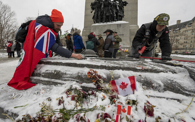 Veterans clear snow and ice off the Tomb of the Unknown Soldier during protests against COVID-19 restrictions on Parliament Hill in Ottawa, Feb. 12, 2022. (Frank Gunn /The Canadian Press via AP)