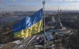 A view of Ukraine's national flag waves above the capital with the Motherland Monument on the right, in Kyiv, February 13, 2022. (AP Photo/Efrem Lukatsky)