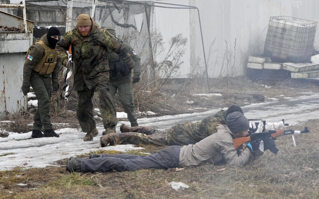 An instructor, second left, runs during a training for civilians and members of the Georgian Legion, a paramilitary unit formed mainly by ethnic Georgian volunteers to fight against Russian forces in Ukraine in 2014, in Kyiv, Ukraine, Feb. 19, 2022. (Efrem Lukatsky/AP)