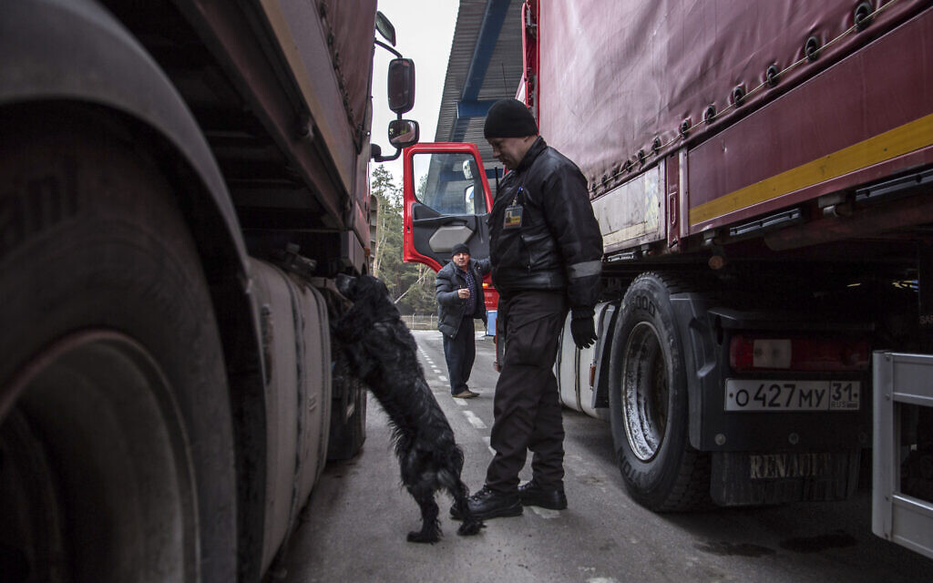 A Ukrainian border guard officer watches as a police dog sniffs a truck at the Ukrainian-Belarusian state border checkpoint Novi Yarylovychi, Ukraine, Feb.21, 2022.(Oleksandr Ratushniak)