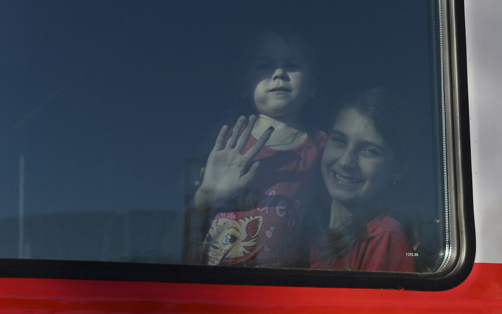 A woman and her child from the Donetsk and Luhansk regions, the territory controlled by pro-Russia separatist governments in eastern Ukraine, waves from a train on their way to temporary shelter in another region of Russia, at the railway station in Taganrog, Russia,  Feb. 21, 2022. (AP Photo)