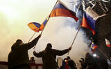 People wave Russian national flags to celebrate, in the center of Donetsk, the territory controlled by pro-Russian militants, eastern Ukraine, late Monday, Feb. 21, 2022. (AP/Alexei Alexandrov)