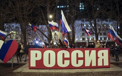 People wave Russian national flags to celebrate, in the center of Donetsk, the territory controlled by pro-Russian militants, eastern Ukraine, late Monday, February 21, 2022. (AP Photo/Alexei Alexandrov)