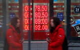 A woman walks by an exchange office screen showing the currency exchange rates of US Dollar and Euro to Russian Rublesin Moscow, on February 22, 2022. (AP Photo/Alexander Zemlianichenko Jr)