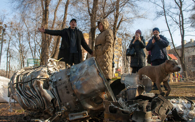People stand next to fragments of military equipment on the street in the aftermath of an apparent Russian strike in Kharkiv in Kharkiv, Ukraine, Feb. 24, 2022. (AP Photo/Andrew Marienko ) People stand next to fragments of military equipment on the street in the aftermath of an apparent Russian strike in Kharkiv in Kharkiv, Ukraine, Feb. 24, 2022. (AP Photo/Andrew Marienko )