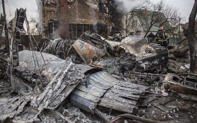 A Ukrainian firefighter walks between at fragments of a downed aircraft seen in in Kyiv, Ukraine, Friday, Feb. 25, 2022 (AP Photo/Oleksandr Ratushniak)