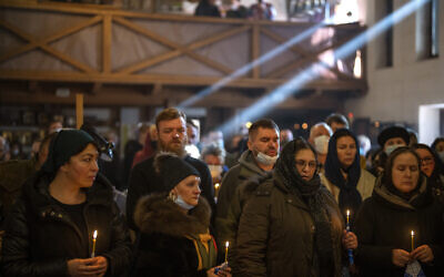 People pray next to the body of Ukrainian Army captain Anton Sydorov, 35, killed in eastern Ukraine, during his funeral in Kyiv, Ukraine, Feb. 22, 2022. (Emilio Morenatti/AP)