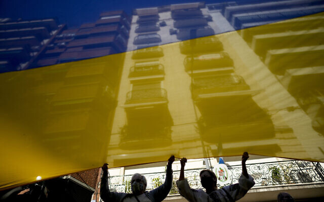 Women help hold up a Ukrainian national flag as they protest against Russia's invasion of the Ukraine, in Buenos Aires, Argentina. Feb. 25, 2022. (Natacha Pisarenko/AP) Women help hold up a Ukrainian national flag as they protest against Russia's invasion of the Ukraine, in Buenos Aires, Argentina. Feb. 25, 2022. (Natacha Pisarenko/AP)