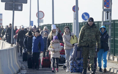 A Polish border guard assists refugees from Ukraine as they arrive to Poland at the Korczowa border crossing, Feb. 26, 2022. (AP Photo/Czarek Sokolowski)