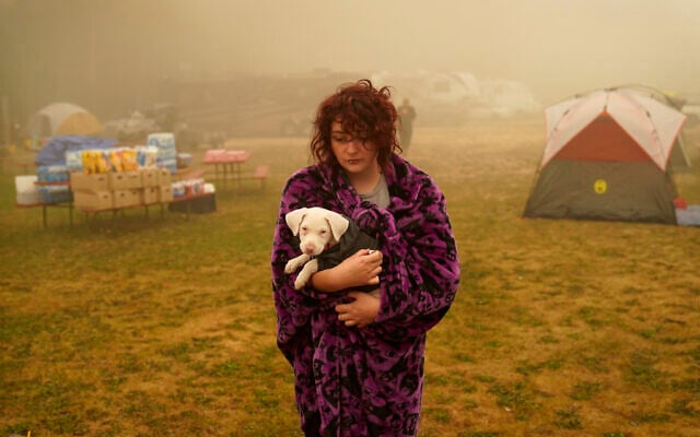 Shayanne Summers holds her dog, Toph, while wrapped in a blanket after several days of staying in a tent at an evacuation center at the Milwaukie-Portland Elks Lodge, in Oak Grove, Ore., Sept. 13, 2020. (John Locher/AP)