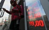 A food delivery man leaves an exchange office with screen showing the currency exchange rates of US dollar and euro to Russian rubles in Moscow, Russia, Feb. 24, 2022. (Alexander Zemlianichenko Jr/AP)
