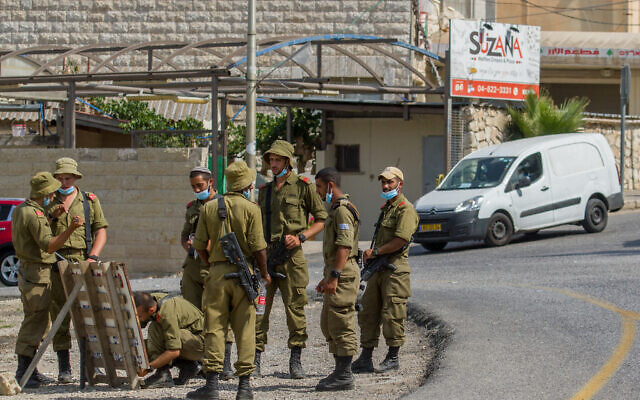 Illustrative: Israeli soldiers wearing face masks are seen at the entrance of Jish, in Northern Israel, July 27, 2020. (Flash90) Illustrative: Israeli soldiers wearing face masks are seen at the entrance of Jish, in Northern Israel, July 27, 2020. (Flash90)