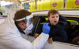 A Magen David Adom worker takes a COVID-19 test sample at a drive through complex in Jerusalem, on January 17, 2022. (Olivier Fitoussi/Flash90)