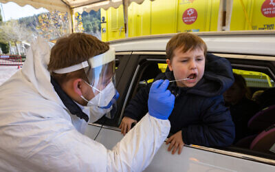 A Magen David Adom worker takes a COVID-19 test sample at a drive through complex in Jerusalem, on January 17, 2022. (Olivier Fitoussi/Flash90)