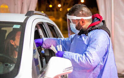 Health care worker takes swab samples from Israelis at a covid-19 drive through testing complex in Modi'in, February 1, 2022. (Yossi Aloni/Flash90) Health care worker takes swab samples from Israelis at a covid-19 drive through testing complex in Modi'in, February 1, 2022. (Yossi Aloni/Flash90)
