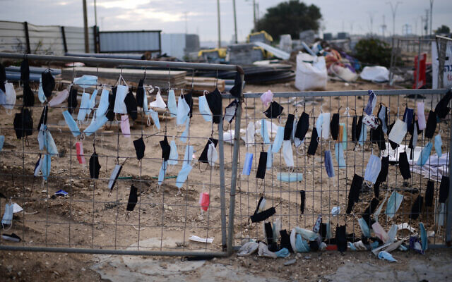 Face masks hang on a fence in Glilot, February 14, 2022. (Tomer Neuberg/ Flash90) Face masks hang on a fence in Glilot, February 14, 2022. (Tomer Neuberg/ Flash90)