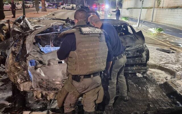 Police sappers and investigators examine the scene of a suspected car bombing in Ashkelon on February 13, 2022 in which one man was killed and two other seriously wounded (Police) Police sappers and investigators examine the scene of a suspected car bombing in Ashkelon on February 13, 2022 in which one man was killed and two other seriously wounded (Police)