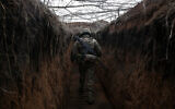 A Ukrainian soldier walks along trench on on the front line with Russia-backed separatists near Novolugansk in the  Donetsk region of Ukraine, February 16, 2022. (Anatolii Stepanov/AFP)
