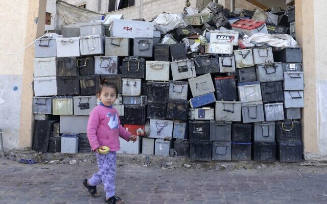 A Palestinian girl walks past a stack of discarded batteries slated for recycling in Khan Yunis in the southern Gaza Strip, on February 14, 2022. (SAID KHATIB / AFP) A Palestinian girl walks past a stack of discarded batteries slated for recycling in Khan Yunis in the southern Gaza Strip, on February 14, 2022. (SAID KHATIB / AFP)
