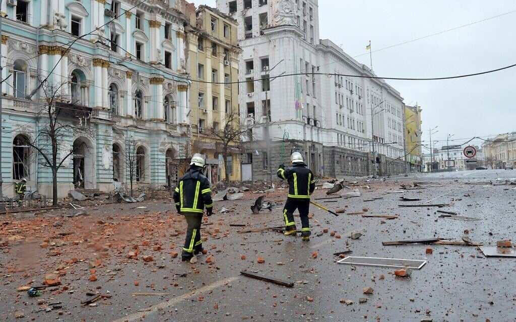 Firefighters walk  among damages after the shelling by Russian forces of Constitution Square in Kharkiv, Ukraine's second-biggest city, on March 2, 2022. (Sergey BOBOK / AFP)