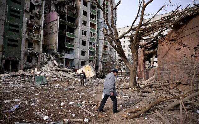 Men walk past a residential building damaged in yesterday's shelling in the city of Chernihiv, on March 4, 2022. (Dimitar Dilkoff/AFP)