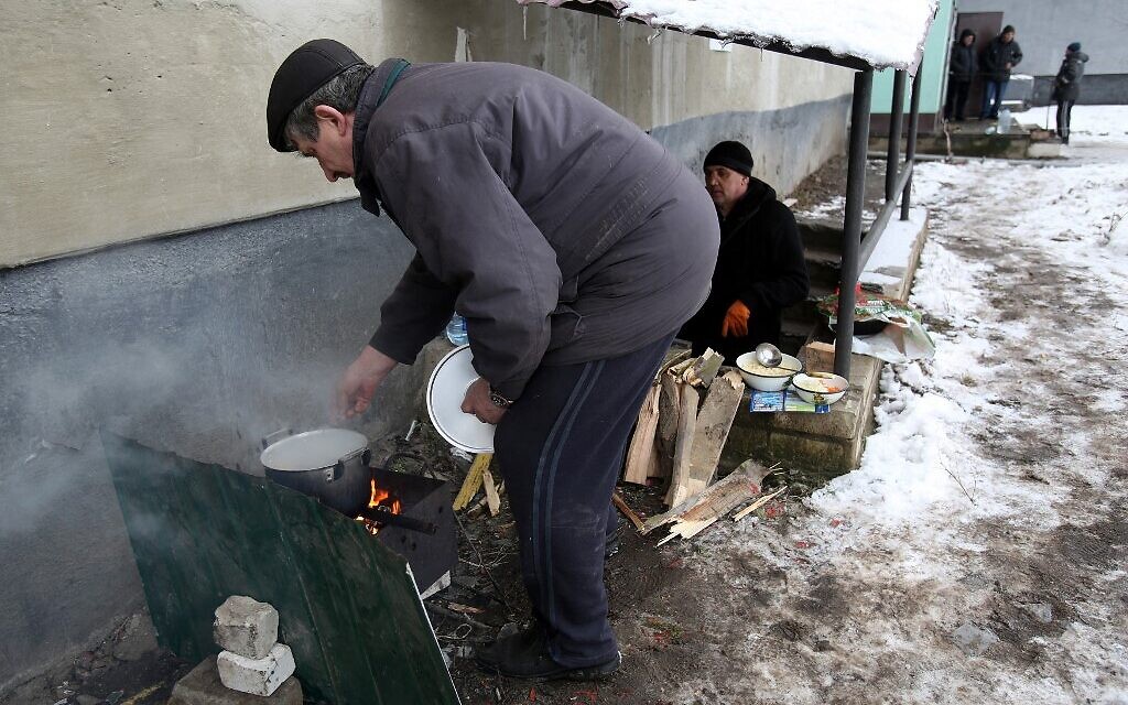 A local resident prepares his food on a fire outside an apartment building in the city of Popasna, Luhansk region on March 5, 2022 as the city left a gas and electricity due regular shelling. (Anatolii Stepanov / AFP)