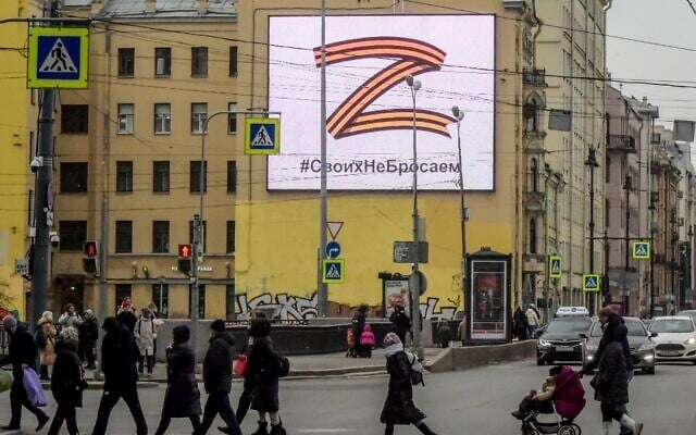 Pedestrians cross a street in front of a billboard displaying the symbol 'Z' in the colors of the ribbon of Saint George and a slogan reading: 'We don't give up on our people,' in support of the Russian armed forces, in Saint Petersburg, on March 7, 2022. (AFP) Pedestrians cross a street in front of a billboard displaying the symbol 'Z' in the colors of the ribbon of Saint George and a slogan reading: 'We don't give up on our people,' in support of the Russian armed forces, in Saint Petersburg, on March 7, 2022. (AFP)