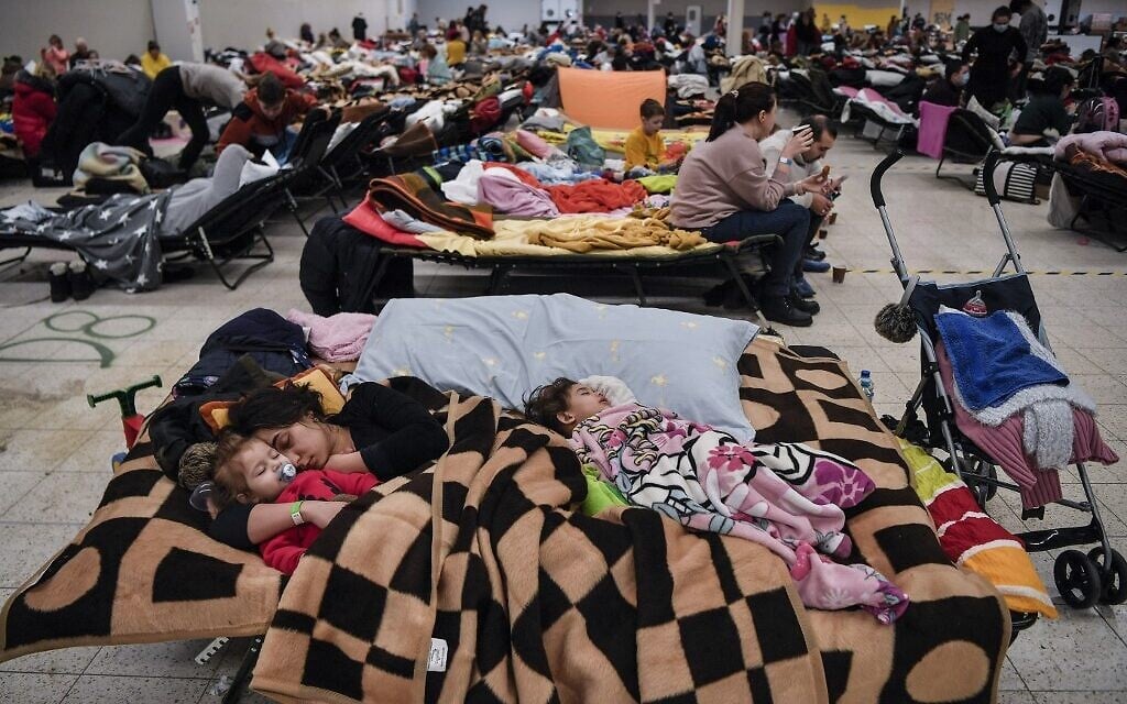 A mother sleeps with her children among many others in a temporary shelter hosting the Ukrainian refugees located in a former shopping center near the city of Przemysl, on March 8, 2022. (Louisa GOULIAMAKI / AFP)