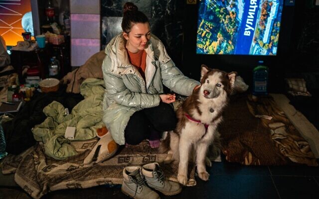 Tania Boyko, 20, and her dog Kari sit on a makeshift bed in a underground metro station used as a bomb shelter in Kyiv on March 8, 2022. (Photo by Dimitar DILKOFF / STF / AFP) Tania Boyko, 20, and her dog Kari sit on a makeshift bed in a underground metro station used as a bomb shelter in Kyiv on March 8, 2022. (Photo by Dimitar DILKOFF / STF / AFP)