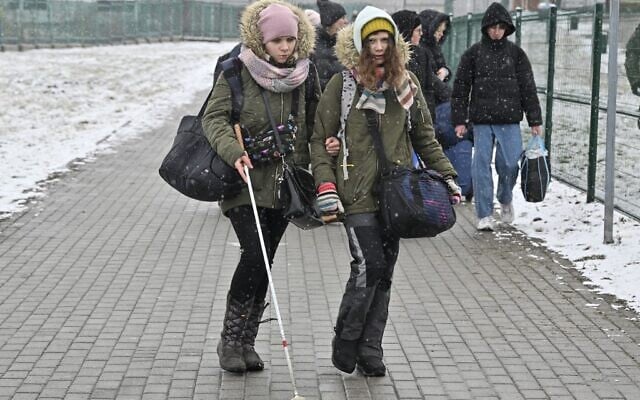 A young woman helps a visually impaired woman as they cross the border from Ukraine into Poland at the Medyka border crossing, eastern Poland, on March 9, 2022 (Louisa GOULIAMAKI / AFP) A young woman helps a visually impaired woman as they cross the border from Ukraine into Poland at the Medyka border crossing, eastern Poland, on March 9, 2022 (Louisa GOULIAMAKI / AFP)