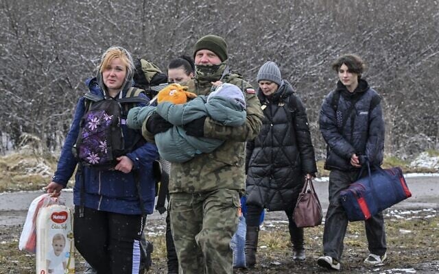A Polish soldier carries a child and helps a refugee family after they crossed the border into Poland from Ukraine at the border crossing in Medyka, eastern Poland, on March 9, 2022 (Louisa GOULIAMAKI / AFP) A Polish soldier carries a child and helps a refugee family after they crossed the border into Poland from Ukraine at the border crossing in Medyka, eastern Poland, on March 9, 2022 (Louisa GOULIAMAKI / AFP)