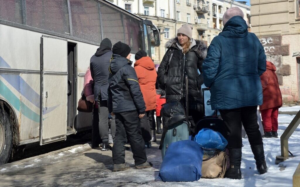 Residents of Kharkiv stand next to a bus as they prepare to evacuate the Ukrainian city on March 12, 2022. (Sergey Bobok/AFP)