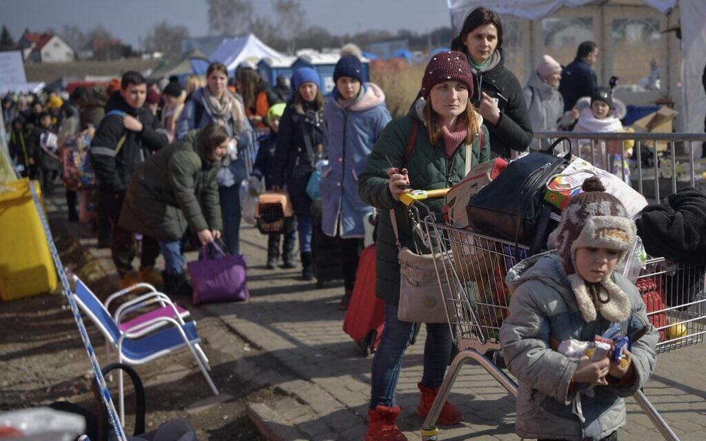 People walk to take further transportation after crossing the Ukrainian border into Poland in Medyka, on March 13, 2022. (Louisa Gouliamaki/AFP)