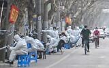 Workers are seen wearing protective clothes next to some lockdown areas after the detection of new cases of COVID-19 in Shanghai, March 14, 2022. (Hector RETAMAL / AFP)