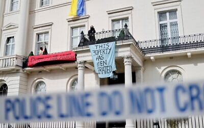 A group of squatters display banners and a Ukrainian national flag on the facade of a mansion supposedly belonging to Russian oligarch Oleg Deripaska in Belgrave Square, central London, on March 14, 2022, as they occupy it. (Tolga Akmen / AFP)