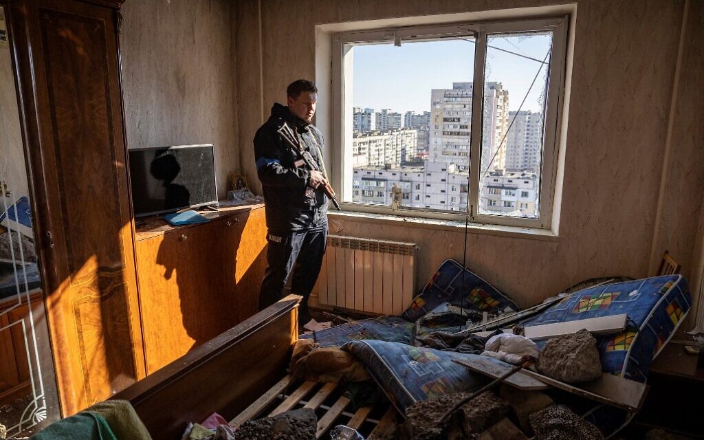 A Ukrainian police officer looks through the window of a damaged apartment in a residential building that was hit by the debris from a downed rocket in Kyiv on March 17, 2022. (Fadel Senna/AFP)
